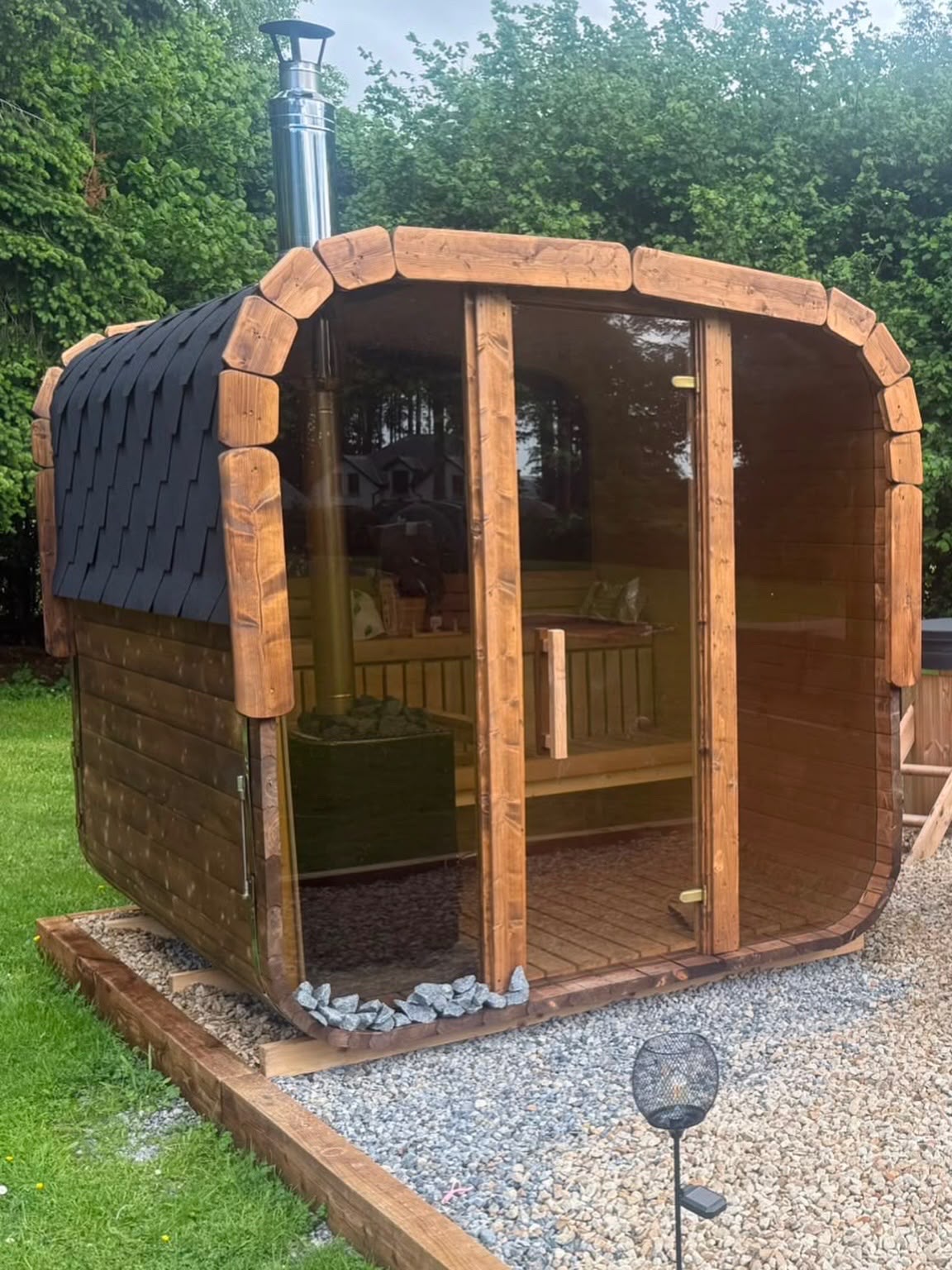 Glass-front outdoor barrel sauna in an Irish garden